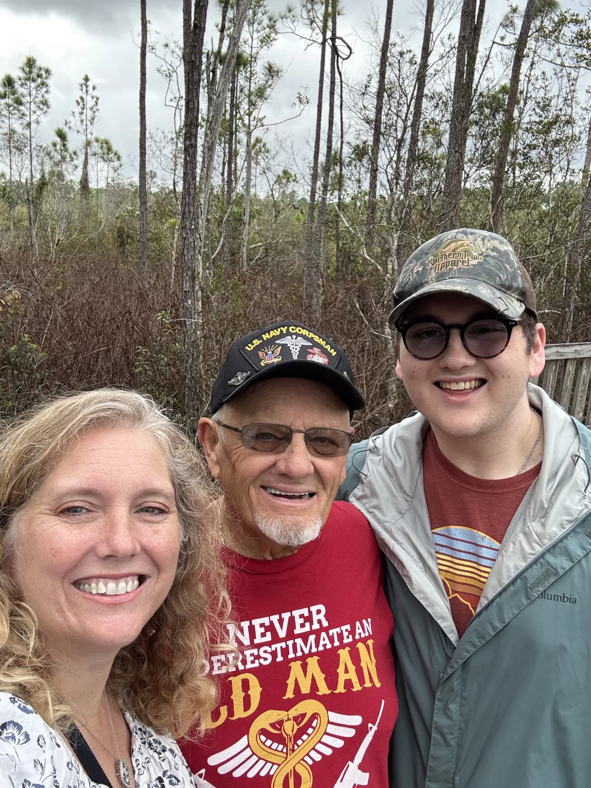 Dennis Myers stands outdoors between two family members.