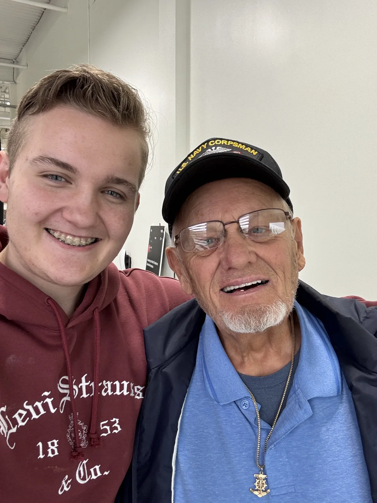 Dennis Myers smiles beside one of his grandchildren while wearing his Navy Corpsman cap.