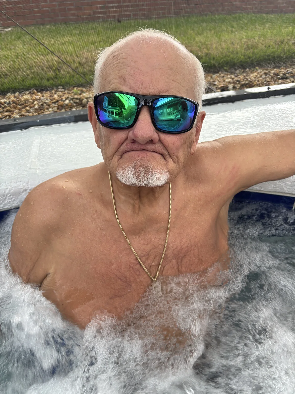 Dennis Myers relaxes in a hot tub wearing mirrored sunglasses.