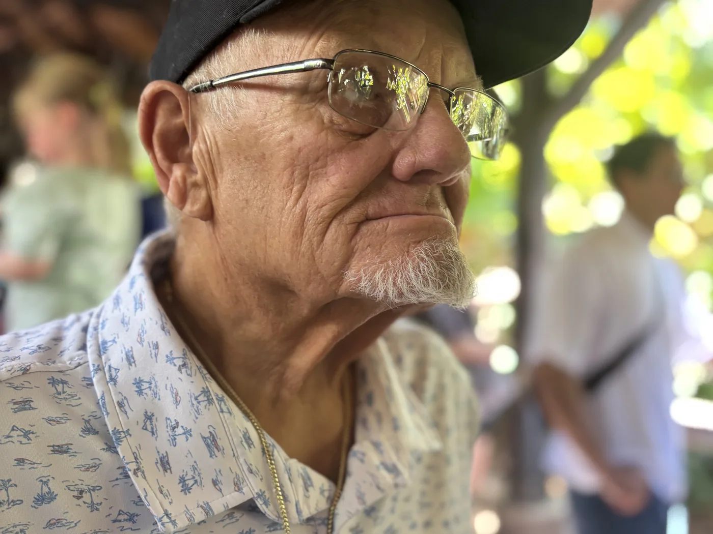 Dennis “Doc” Myers in a patterned shirt and Navy cap, looking across the room